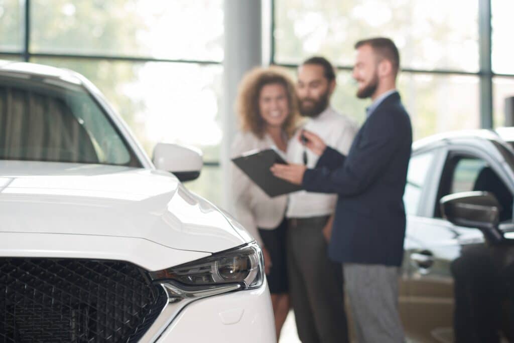 Car dealer discussing purchase of car with clients